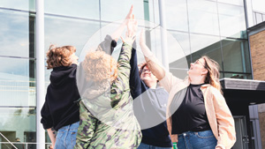 Fyra studenter gör high five utanför lindellhallen